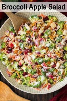 a salad with broccoli, apples and cranberries in a white bowl