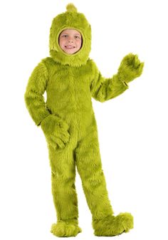 a little boy in a green costume standing with his hands out and smiling at the camera