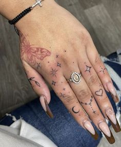 a woman's hand with tattoos on it and a cross tattooed on the middle finger