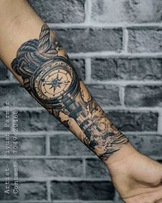 a man's arm with a compass tattoo on it