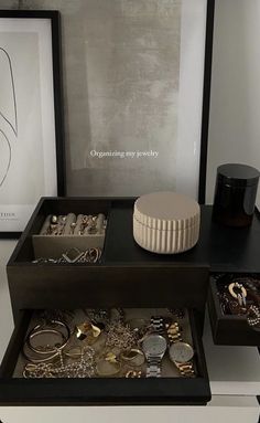 an assortment of jewelry sits on display in a black and white box next to a framed photograph