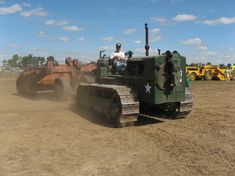 a man driving a tractor on top of a dirt field