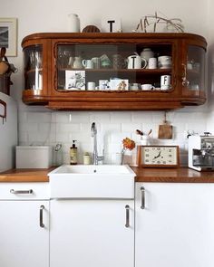 a kitchen with white cabinets and wooden counter tops is pictured in this image, there is a clock on the cabinet above the sink