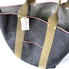 a denim tote bag with two straps and a tag on it