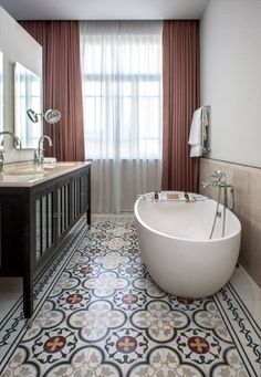 a bath tub sitting next to a window in a bathroom on top of a tiled floor