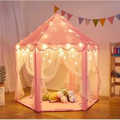 a pink tent with lights and stuffed animals