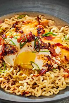 a bowl filled with noodles and meat topped with an egg