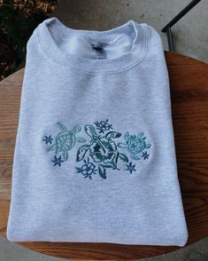 Tropical Turtles Embroidered Sweatshirt! -Embroidered on a cotton/polyester blend crewneck sweatshirt, this design is simple and minimalistic, perfect for every outfit! -Embroidery design measures . -See product pictures for shirt sizing chart. **SWEATSHIRTS ARE IN UNISEX SIZING AND RUN TRUE TO SIZE. -All sweatshirts are handmade on an embroidery machine so there may be slight differences, but we only sell the sweatshirts that meet our high-quality standards. -To maintain the quality of your sweatshirt and the embroidery design make sure to wash with care. We recommend turning the item inside out and using a cold wash and delicate cycle. We highly recommend air drying when possible as well. -Please feel free to reach out with any additional questions, customization requests, etc. We will d Embroidery Disney Designs, Casual Crew Top With Machine Embroidery, Crew Cotton Sweatshirt With Machine Embroidery, Cotton Crew Sweatshirt With Machine Embroidery, Crew Neck Cotton Sweatshirt With Machine Embroidery, Cotton Crew Neck Sweatshirt With Machine Embroidery, Basic Crew Neck Sweatshirt With Embroidered Graphics, Embroidered Gray Crew Sweatshirt, Gray Embroidered Crew Sweatshirt