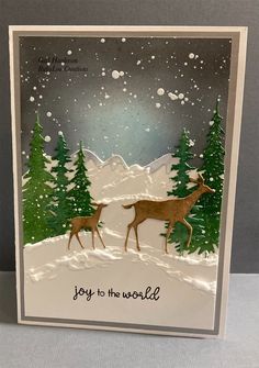 a handmade christmas card with two deers in the snow and trees on it