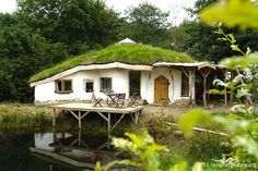 a white house with a green roof next to a body of water