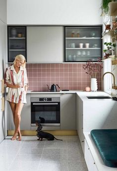 a woman standing in a kitchen next to a black cat