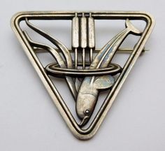 We offer a wonderful Georg Jensen Sterling Silver Brooch/Pin in the scarce pattern number 257. This a wonderful Art Deco piece that was designed by Arno Malinowski in the 1930's and is consists of a diving Dolphin with cattails in a triangular frame. This lovely piece is in superb condition, the sturdy rollover pin is secure and will prevent loss. As the photos demonstrate, this lovely piece has a slight patina. The Brooch measures 1 5/8's inches on each side and weighs approx. 11 grams. We beli Modernist Silver Jewelry, Georg Jensen Jewelry, Lapel Brooch, Silver Brooch Pin, Art Deco Brooch, Modernist Jewelry, Sterling Silver Brooch, Georg Jensen, Silver Brooch