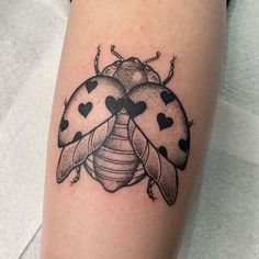 a ladybug tattoo on the leg with hearts and two bugs sitting on it