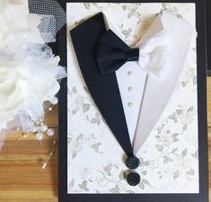 a card with a tuxedo and bow tie on it next to some flowers