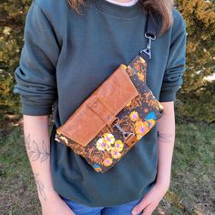 a woman holding a brown purse in her right hand and wearing blue jeans on the other side