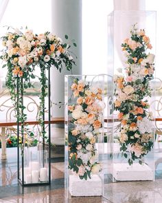 two clear vases filled with flowers on top of a marble floor next to candles