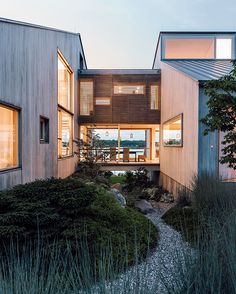 the house is made out of wood and has many windows on each side, along with plants