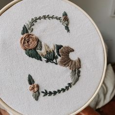 a hand embroidered letter s with flowers on it