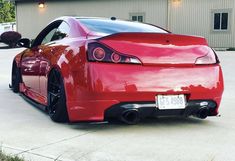 a red sports car parked in front of a building with its rear end turned to the side