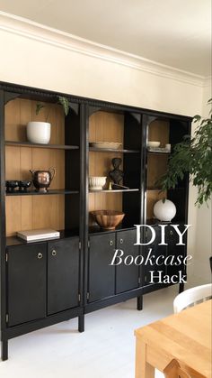 a black bookcase with glass doors and drawers in a living room next to a potted plant