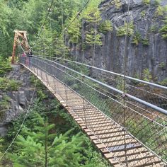 people walking across a suspension bridge over a river