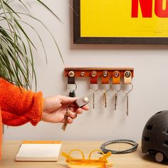 a person holding keys in front of a wall mounted key rack