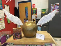 a gold vase with white feathers on top of it in a classroom setting for children to learn