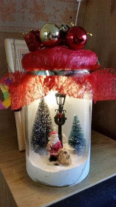 a glass jar filled with christmas decorations on top of a table