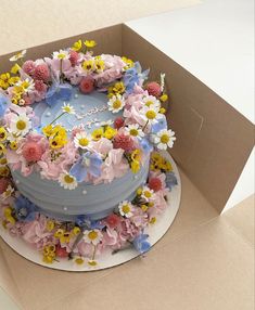 a blue cake decorated with flowers in a box