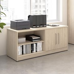 a computer desk with printer, scanner and other office supplies on it in front of a window