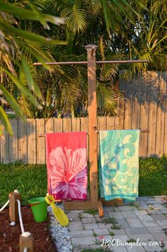 two towels are hanging on a clothes line in the back yard, next to a pool