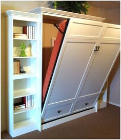 a white bookcase with an open door on the bottom and shelves below it, in a room with carpeted flooring