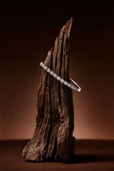 a white diamond ring sitting on top of a piece of wood with a brown background