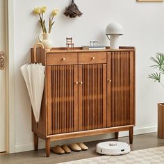 a wooden cabinet sitting on top of a hard wood floor next to a white wall