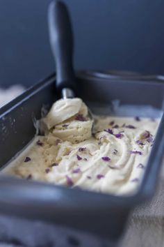 a scoop of ice cream in a pan with purple flowers on it and a spoon