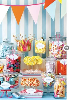 an assortment of candy and candies displayed on a table in front of striped wallpaper