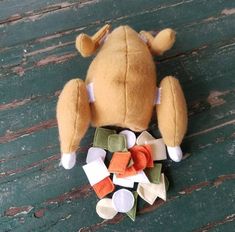 a stuffed animal that is laying on the ground next to some pieces of fabric and buttons