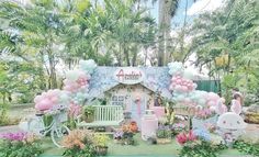 a small house with balloons and flowers in the front yard, surrounded by palm trees