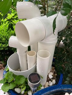 there are many white vases and plants in the potted planter with rocks