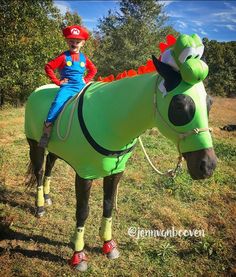 a young boy riding on the back of a green horse wearing a mario bros costume