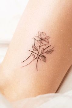 a small tattoo on the leg of a woman's thigh with flowers in it