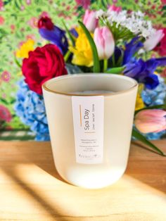 a white cup filled with flowers on top of a wooden table