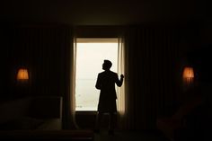 a man standing in front of a window looking out at the ocean