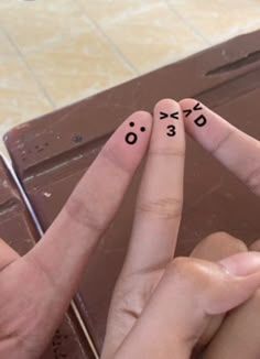 two fingers with faces drawn on them are pointing at each other's fingers,