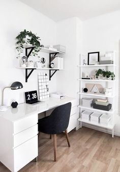 a white desk topped with a black chair next to a shelf filled with books and plants