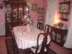 a dining room with pink walls and white table cloths set for a formal dinner