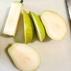 an apple sliced in half on top of a cutting board with a knife next to it