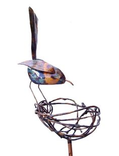 a metal bird sitting on top of a wire nest