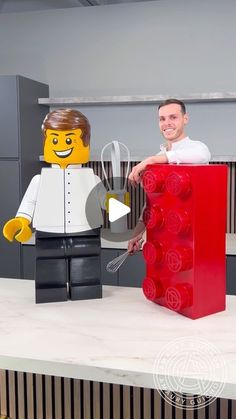 a man standing next to a giant lego block holding a knife and fork in his hand