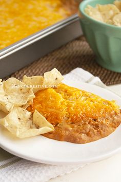 an enchilada with tortilla chips on a plate next to a bowl of salsa